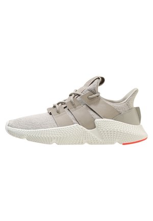 Baskets de sport gris clair avec tige en maille, semelle épaisse texturée et larges bandes de lacets, vues de profil sur fond blanc.