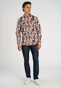 Langarmshirt met een kleurrijke dierenprint en sneeuwvlokken, gemaakt van lichtgewicht stof. Gepaard met donkere jeans en witte sneakers.