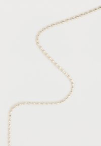 Ασημένια μεταλλική αλυσίδα με σφαιρικές χάντρες κυρτή πάνω σε λευκό απλό φόντο, εμφανίζοντας συνδεδεμένες σφαιρικές χάντρες σε συνεχή γραμμή.