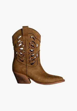 Bota vaquera de ante marrón con patrones florales recortados, tacón apilado inclinado y punta puntiaguda, vista de perfil sobre fondo blanco.