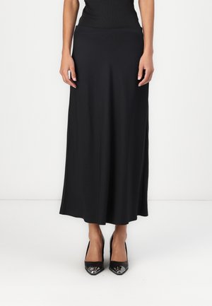 Schwarzer Midirock aus glattem, dehnbarem Stoff mit einer schmeichelhaften Silhouette, kombiniert mit schwarzen Pumps mit spitzem Schuh und metallischen Akzenten.