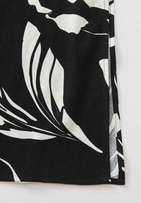 Tissu noir et blanc avec un grand motif floral abstrait et une couture visible le long du bord.