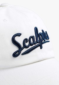 Witte pet met marineblauwe geborduurde tekst "Scalper." Heeft een gestructureerde vorm en een textuur oppervlak, ontworpen voor casual gebruik.