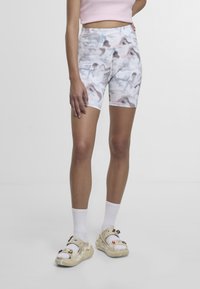 Sopivat pyöräilyshortsit pastellinsävyisellä marmorikuvioinnilla, jossa on vaaleanpunaisia ja harmaita sävyjä. Yhdistetty koristeltuihin liukusandaaleihin ja valkoisiin keskipitkiin sukkiin.