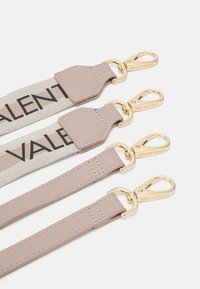 Kožené popruhy v béžové a světle růžové barvě, s kovovými zlatými sponami. Jeden popruh má plátěnou část s nápisem "VALENTINO" černě.