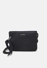 Černá nylonová crossbody taška s zipovým uzávěrem, propletenou rukojetí a kovovými akcenty s logem na přední straně. Hladký povrch.