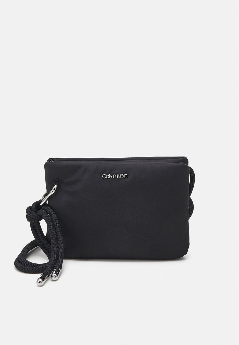 Černá nylonová crossbody taška s zipovým uzávěrem, propletenou rukojetí a kovovými akcenty s logem na přední straně. Hladký povrch.