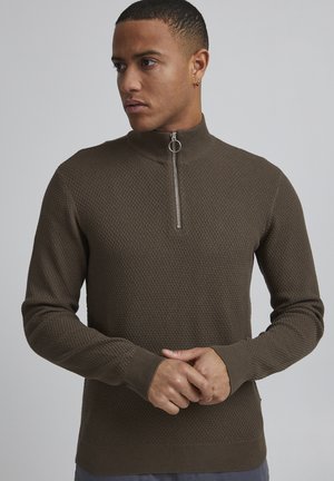 Sudadera con cremallera texturizada marrón, con un alto cuello y tirador de cremallera circular. Mangas y cintura ajustadas, adecuada para usar en ocasiones informales.