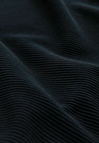 Czarna ribbed tkanina z teksturowanym wzorem falistym, z drobnymi poziomymi żłobieniami, które tworzą głębię i wizualne zainteresowanie.