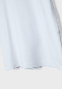 Tissu bleu clair avec une couture visible et de légers plis sur un fond uni clair.