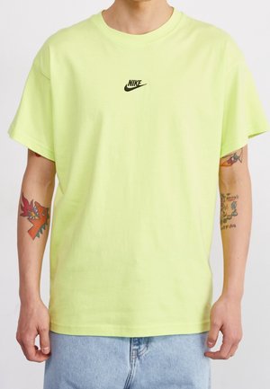 Neon-grünes Kurzarm-T-Shirt aus Baumwolle mit rundem Ausschnitt. Verfügt über ein kleines schwarzes Nike-Logo, das auf der Brust zentriert ist.