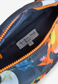 Värikäs, kuvioitu laukun sisusta, jossa on tummansininen kangas, oranssi vetoketju ja musta vuori. Sisältää kiinnitetyn merkin, jossa on brändi- ja hoito-ohjeet.