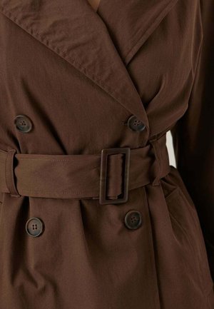 Trench coat doppiopetto marrone con ampie faldine, quattro bottoni, cintura di stoffa con fibbia rettangolare e tasche laterali.