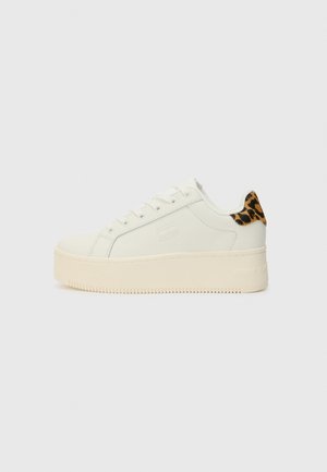 Biały niski sneaker z grubą beżową podeszwą, detalem w panterkę na pięcie, tłoczonym logo na boku i białymi sznurowadłami.