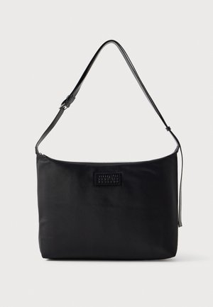 Sac à bandoulière rectangulaire noir, doté d’une longue bandoulière réglable et d’une petite plaque avec logo à l’avant.