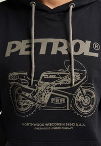 Felpa nera con design grafico grigio raffigurante una motocicletta e la parola "PETROL." Include cordoncini e testo con marchio nella parte inferiore.
