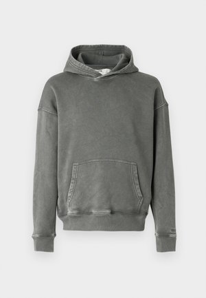 Sivi dukserica napravljena od tkanine s mekom teksturom. Ima prednji džep, široke manžetne i podesivu kapuljaču s vezicom.