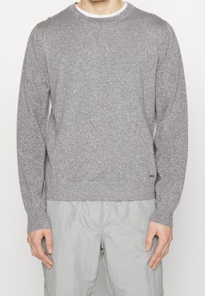 Stříbrný třpytivý svetr s kulatým výstřihem, dlouhými rukávy a žebrovanými manžetami. Měkká textura s jemným, třpytivým vzorem po celé ploše.