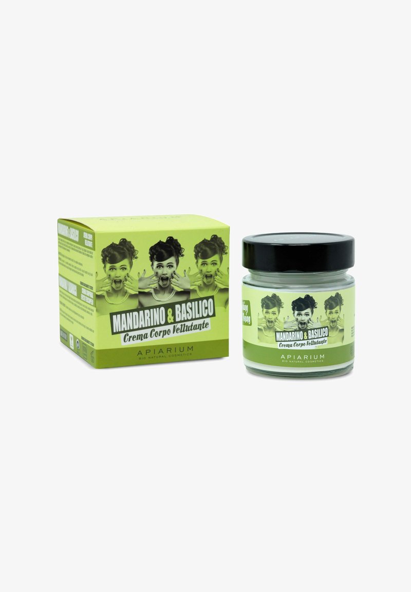 Barattolo di crema per il corpo e scatola di colore verde vivace, decorate con immagini vintage in bianco e nero. L'etichetta riporta "Mandarino & Basilico" in carattere bianco in grassetto.