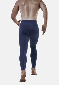 Blauwe sportleggings met een gestructureerd onderste gedeelte, voorzien van een achterzak en een elastische tailleband. Gemaakt van een glad, ademend materiaal.