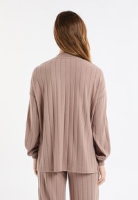 Jasnoróżowy prążkowany sweter z długimi rękawami i okrągłym dekoltem. Charakteryzuje się luźnym krojem i fakturowaną tkaniną podkreślającą pionowe linie.