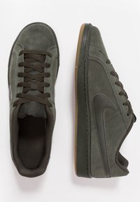 Zelené semišové tenisky s strukturálním povrchem, kulatou špičkou, gumovou podrážkou a tmavými tkani�čkami. Na boku se nachází šedé logo swoosh.