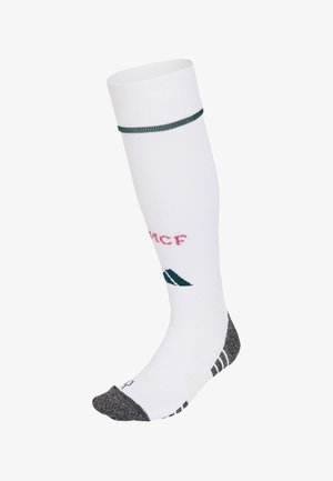 Chaussette de sport blanche montant jusqu'au genou avec un bout et un talon gris foncé, une bande verte près du haut et le texte rose « MCF » sur le mollet.