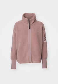 Fleece jacket in soft light pink with a high collar, half-zip front, and ribbed cuffs. Features a subtle logo detail on the sleeve.