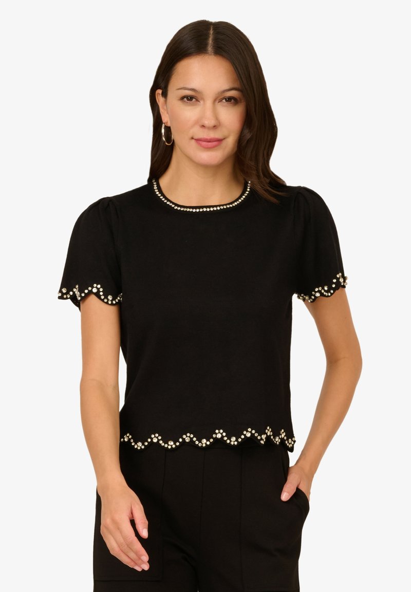 Černé tričko s krátkým rukávem a kulatým výstřihem, zdobené perlovými akcenty podél lemu a rukávů, s vlnitým designem.