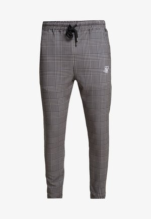 Jogging en tartan noir et blanc avec une taille élastique, cordon de serrage, et un petit logo sur la jambe gauche. Matière en mélange coton.