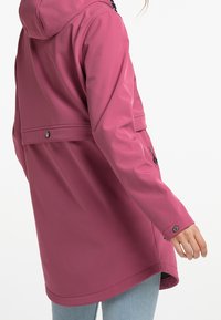Chaqueta impermeable rosa con capucha, que cuenta con un cierre a presión, puños ajustables y un corte relajado. Textura suave y brillante y diseño de longitud media.