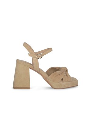 Sandali platform in suede beige con dettaglio di nodo frontale e tacco a blocco largo. Cinturino alla caviglia regolabile con fibbia metallica circolare.