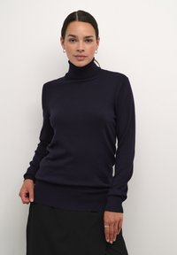 Navyblauwe coltrui van zachte stof, met lange mouwen, een getailleerd ontwerp en geribbelde manchetten en zoom. Glad textuur.