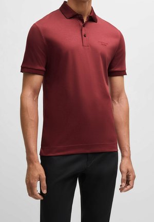 Kurzärmliges Poloshirt in Burgunderrot mit klassischem Kragen und dezentem Logo. Hergestellt aus glattem Stoff mit gerippten Akzenten an Ärmeln und Saum.