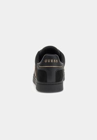 Adidași negri cu superior din suede și material sintetic, guler căptușit, talpă din cauciuc și marcaj aurie "GUESS" pe călcâi.