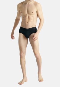 Svarta simkalsonger i mjukt tyg; har ett brett elastiskt midjeband med diskret varumärkeslogotyp. Utformade för en åtsittande silhuett.