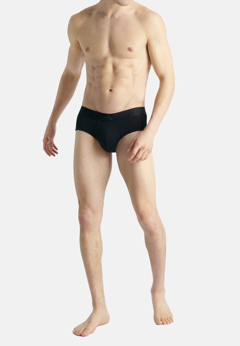 Svarta simkalsonger i mjukt tyg; har ett brett elastiskt midjeband med diskret varumärkeslogotyp. Utformade för en åtsittande silhuett.