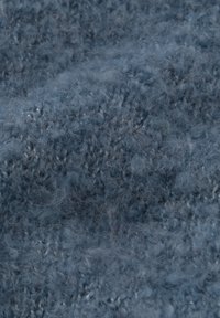 Blødt, tekstureret stof i en afdæmpet blå farve med et lodent, uregelmæssigt strikkemønster med små løkker og varierende tykkelse over det hele.