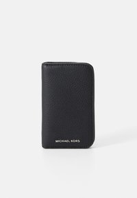 Svart lærpung med teksturert overflate, rektangulær form og hvit "MICHAEL KORS"-logo nederst.Minimalistisk design.