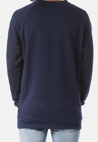Sudadera azul marino de manga larga y cuello redondo. Textura suave con puños y dobladillo acanalados, que presenta un corte relajado.