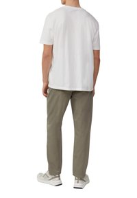 Biała bawełniana koszulka z krótkim rękawem, połączona z jasnymi oliwkowymi spodniami i białymi trampkami z szarymi akcentami. Prosty, luźny krój.