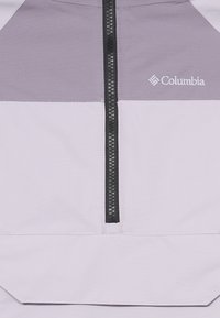 Ľahký pulóver fialovej a šedej farby s polovičným zipsom. Má hladkú matnú textíliu a malé logo Columbia na ľavej strane.