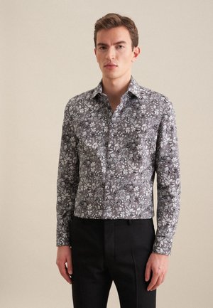 Chemise à manches longues en tissu gris avec un motif floral en blanc et noir. Présente un col pointu et une fermeture à boutons sur le devant.