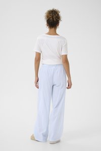 T-shirt bianco a maniche corte abbinato a pantaloni larghi a righe verticali blu chiaro. Texture morbida e dettaglio della cintura elastica.