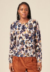 Maglione lavorato a maglia con motivi floreali, caratterizzato da un collo rotondo, maniche lunghe e fantasie multicolori in blu, giallo e rosa su uno sfondo bianco.