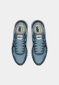 Kék hálós futócipők sötétkék részletekkel. Fűzős kialakítással, párnázott nyelvvel és "ASICS" márkázással a nyelven és a talpbetéten.
