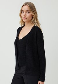 Cardigan nero realizzato in materiale a maglia finemente strutturato. Design con apertura frontale, maniche lunghe e vestibilità rilassata. Top a V sottostante.