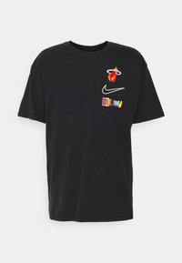 Camiseta de algodón negra con mangas cortas que presenta el logo de Miami Heat, el swoosh de Nike y el texto colorido "miami" impreso en el frente.
