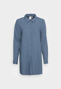 Chemise à manches longues et à boutons dans une couleur bleu atténuée, confectionnée dans un tissu léger. Présente un col classique et une coupe droite avec des détails de boutons.