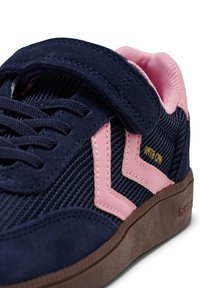 Granatowy tenisówka z różowymi akcentami, rzepem, teksturowanym sztruksem i gładkimi powierzchniami, gumowa podeszwa z wyraźnym wzorem bieżnika.